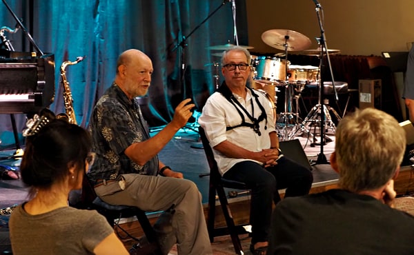 Art talks and gestures to students while seated